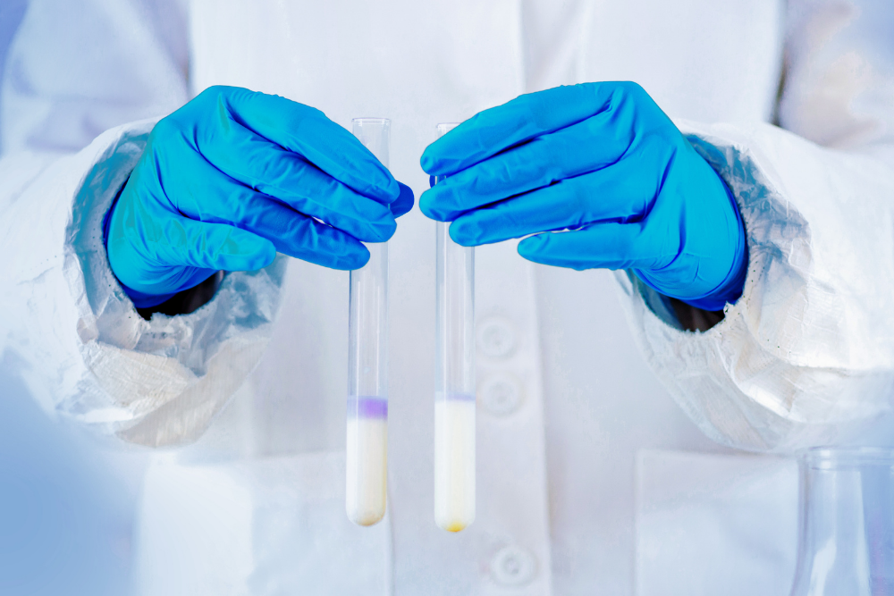 Científico con guantes azules sosteniendo dos tubos de ensayo en un laboratorio, relacionado con conceptos básicos de metrología